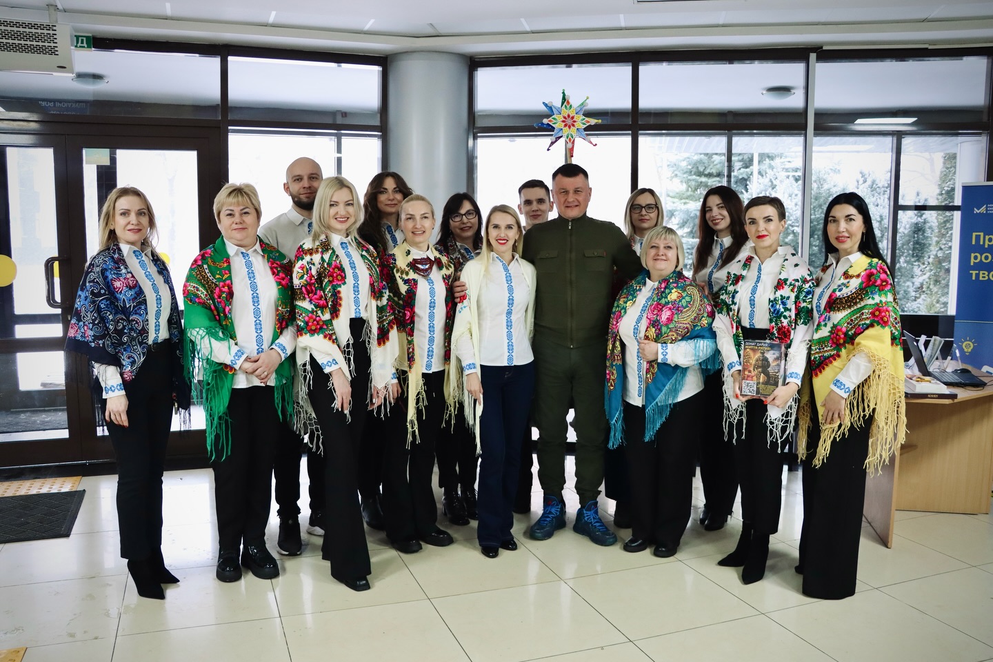 Група людей у вишитих сорочках та чоловік у зеленому одязі. 