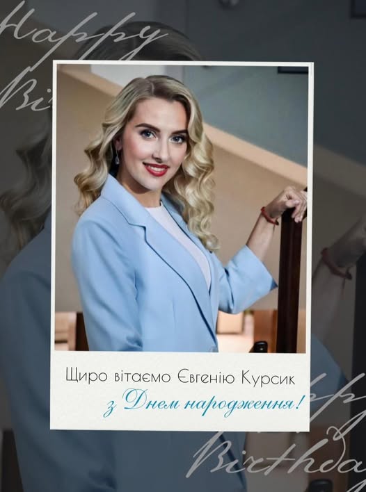 Жінка зі світлим волоссям в блакитному костюмі посміхається.