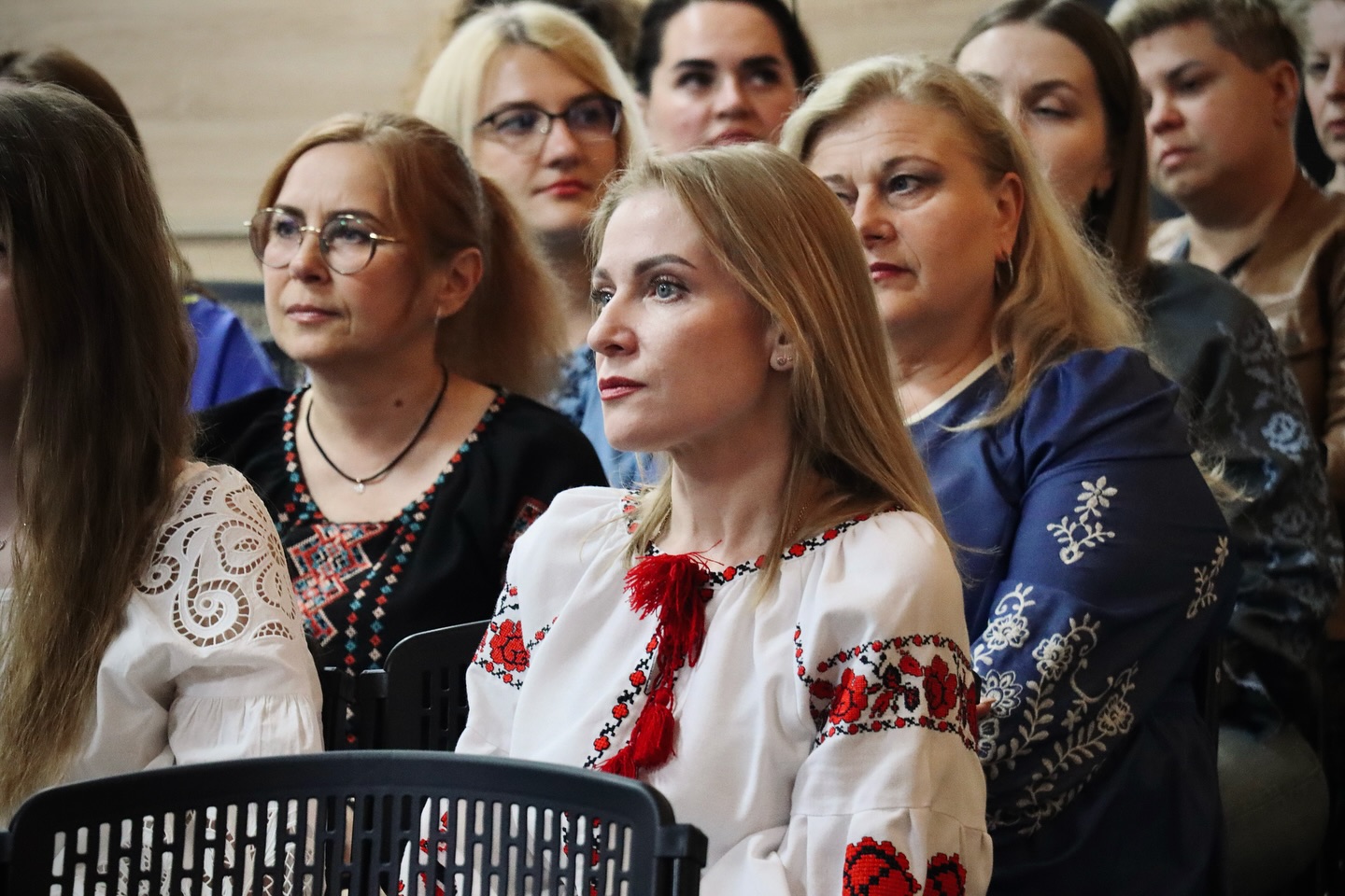 Жінки у вишитому одязі сидять у залі.