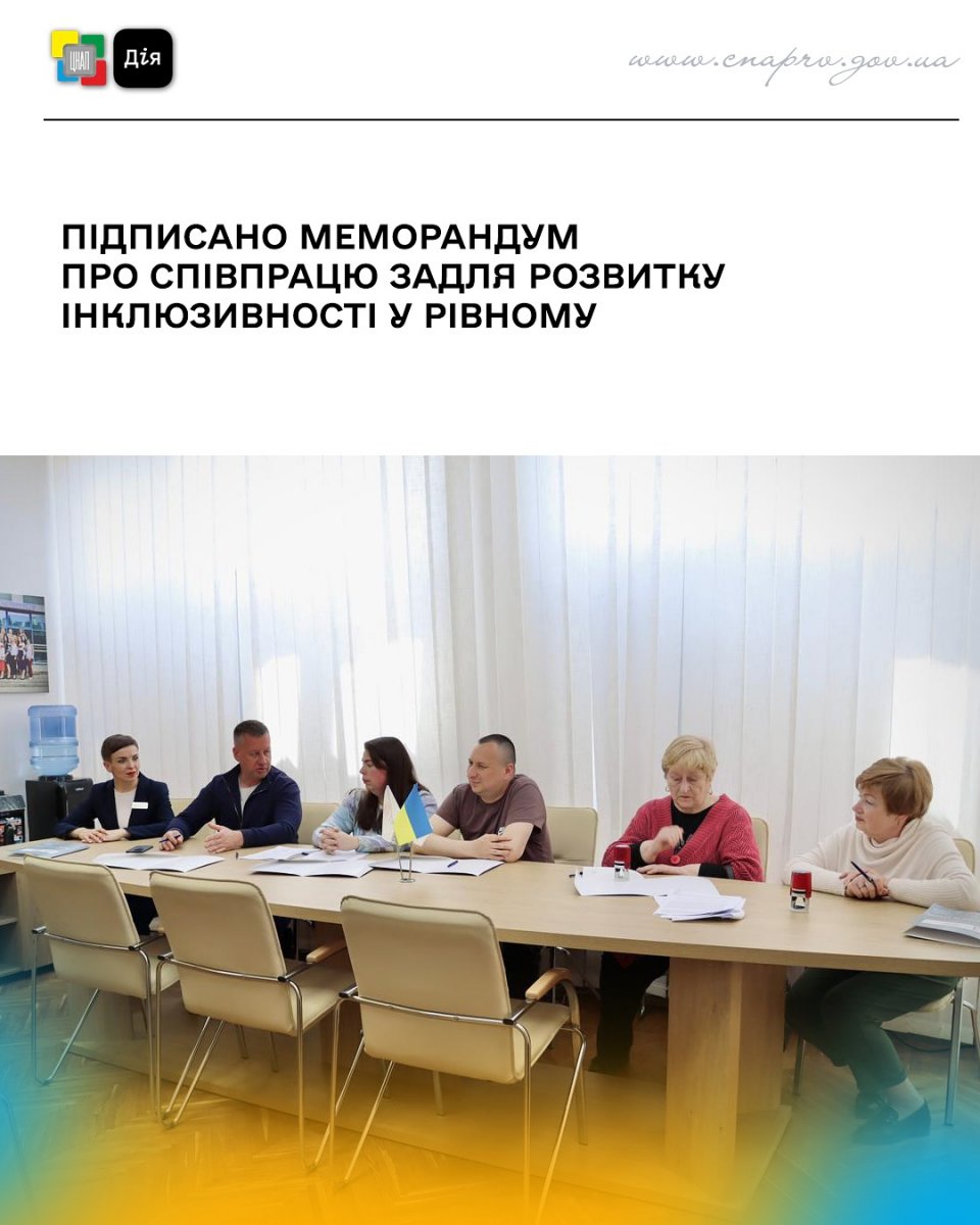  Шість людей сидять за столом з документами, в центрі — прапорець України.