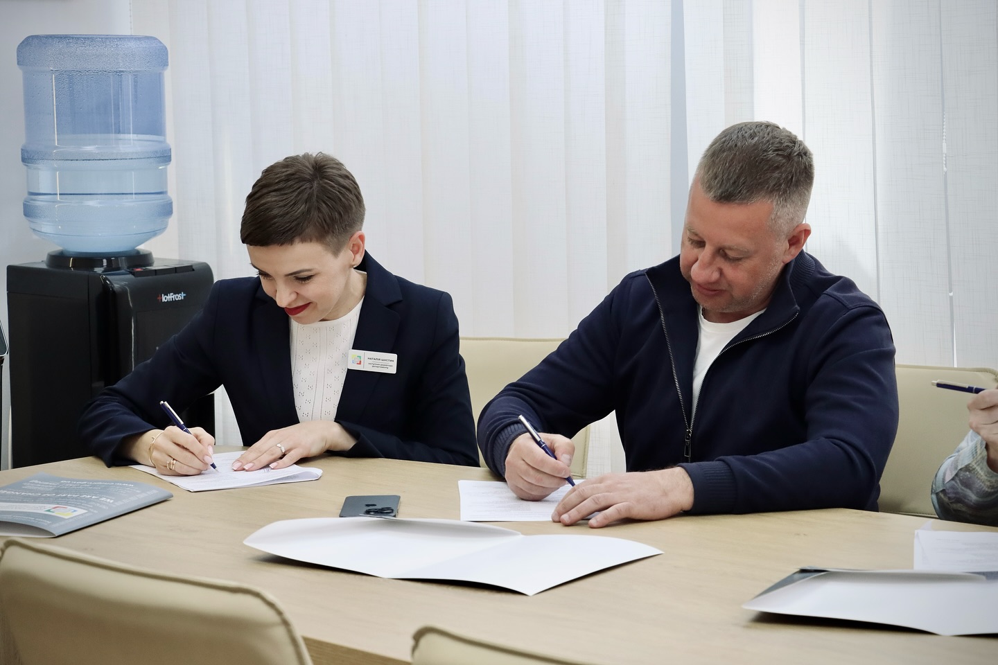 Чоловік та жінка сидять за столом та щось пишуть.