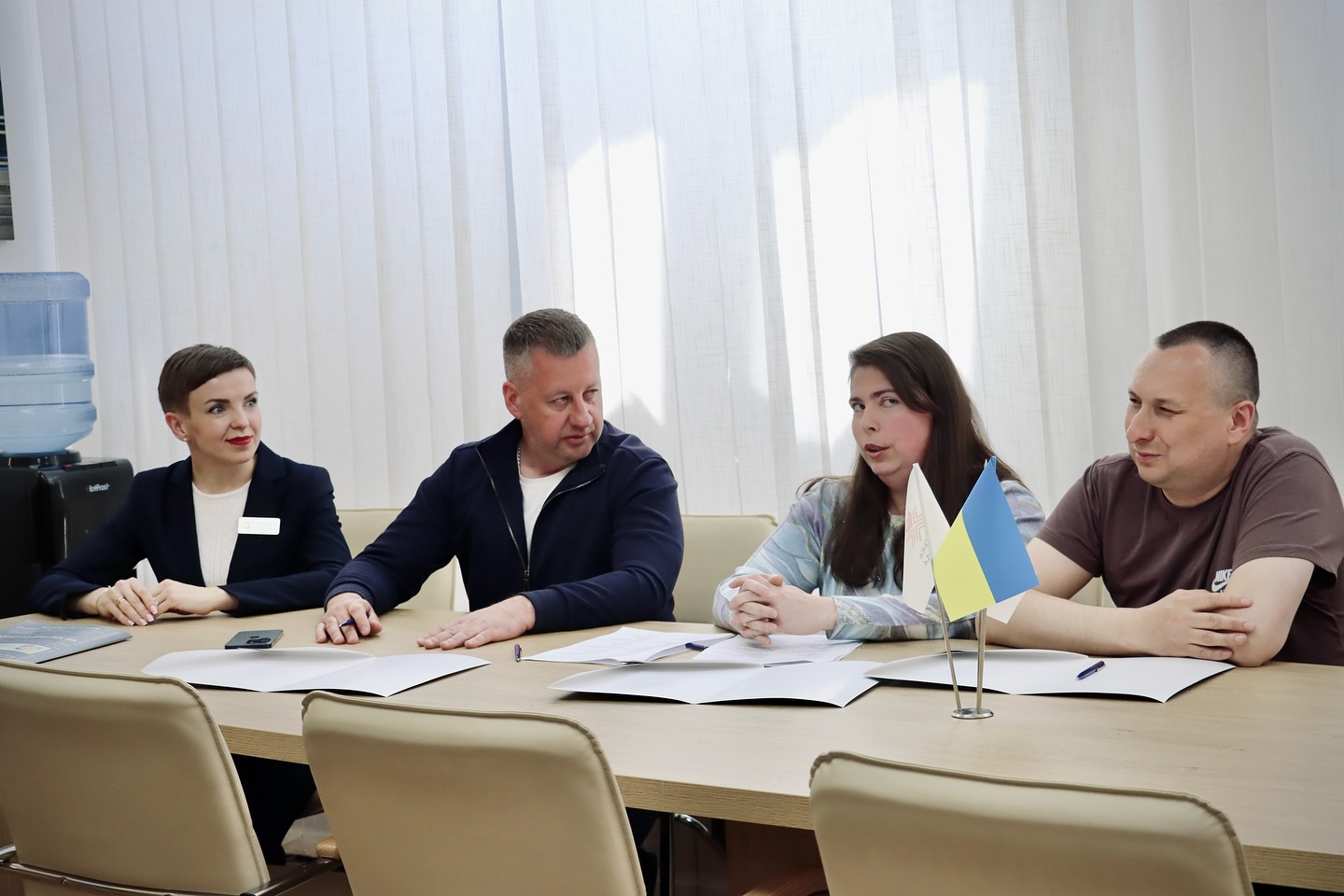 Двоє чоловіків та дві жінки сидять за столом у кабінеті.