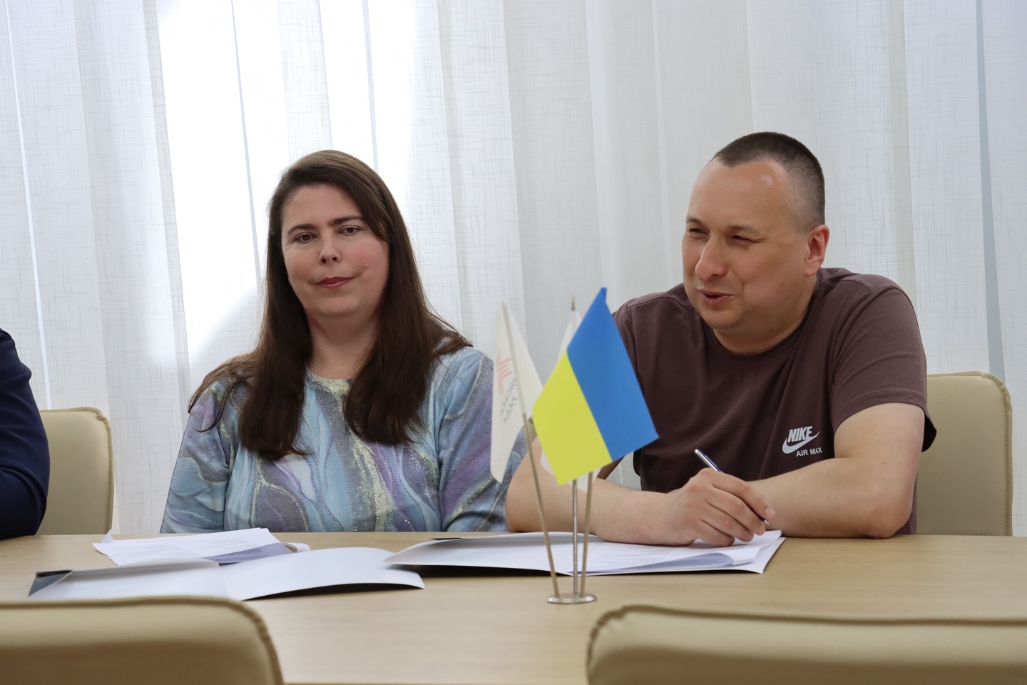 Жінка та чоловік сидять усміхнені за столом.