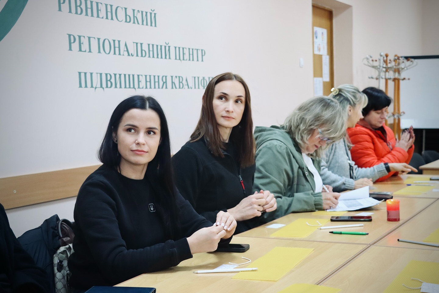 Група жінок сидять за столом у приміщенні.