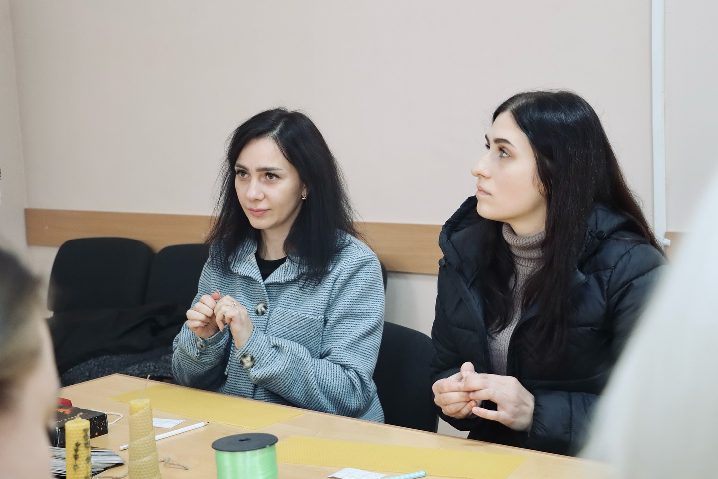 Дві жінки з темним волоссям сидять за столом.