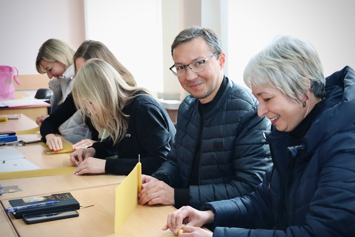 Група людей сидить за столом та роблять свічки.