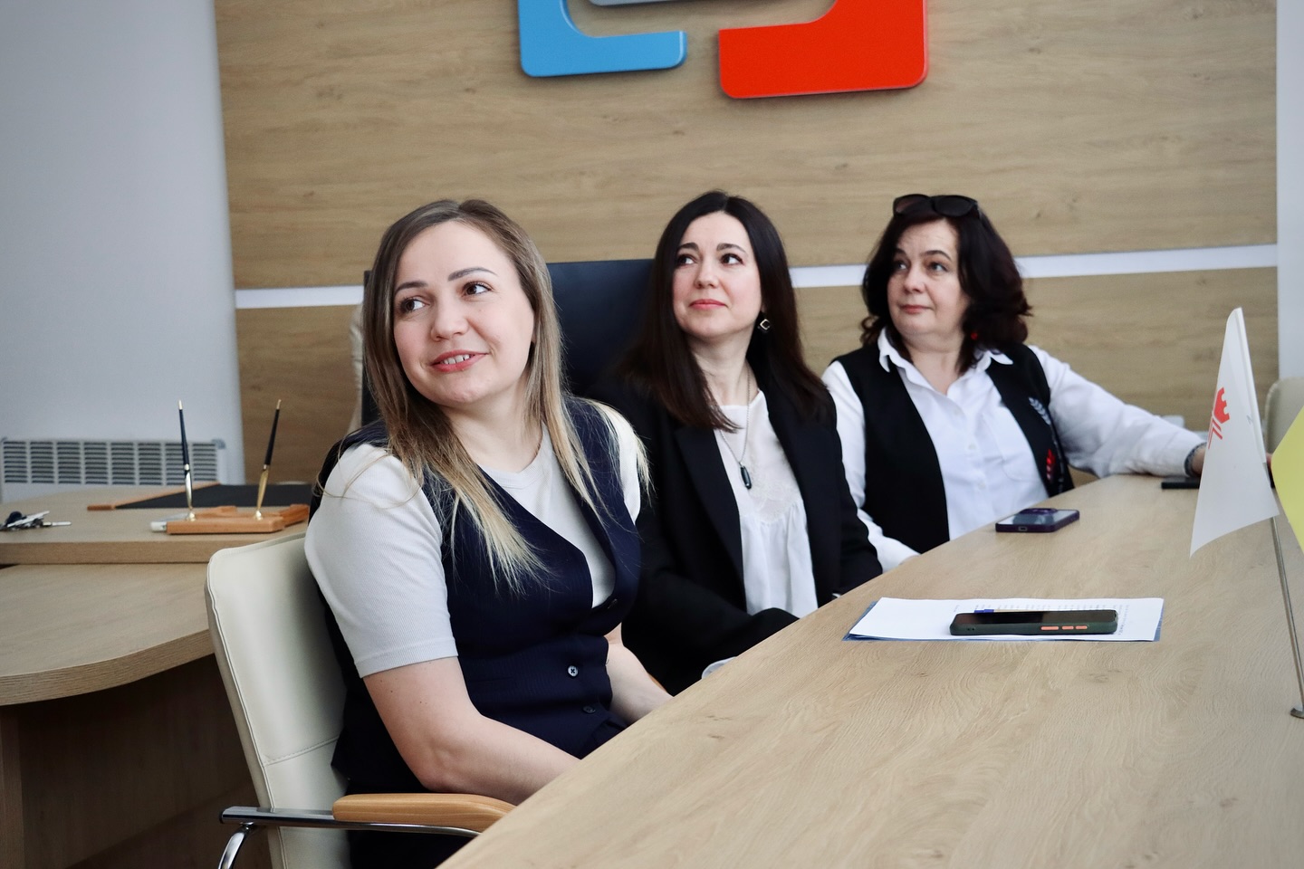 Три жінки сидять у кабінеті та дивляться убік.