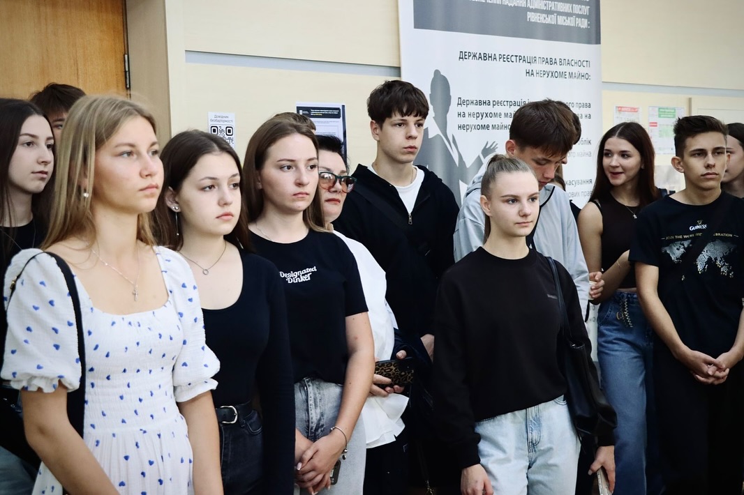 Група молодих людей стоїть у приміщенні, на задньому плані видно інформаційний банер.