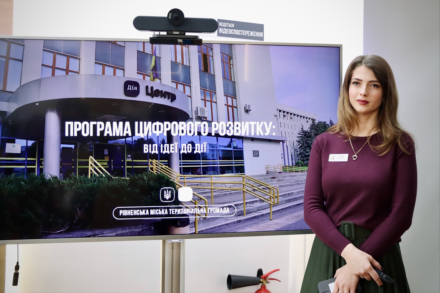 Жінка стоїть біля телевізора.