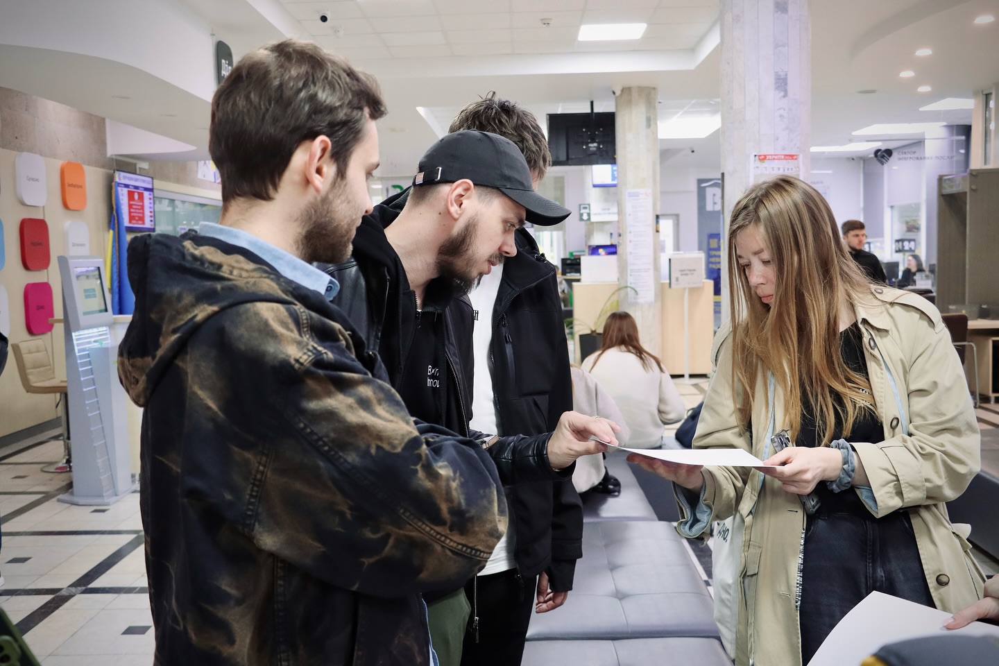 Жінка та троє чоловіків розглядають щось на папері.