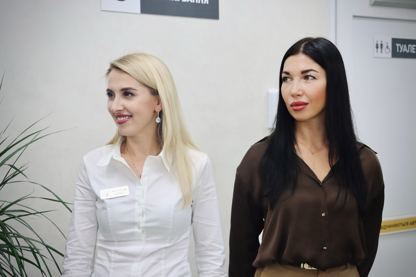 Дві жінки у діловому одязі перебувають у приміщенні