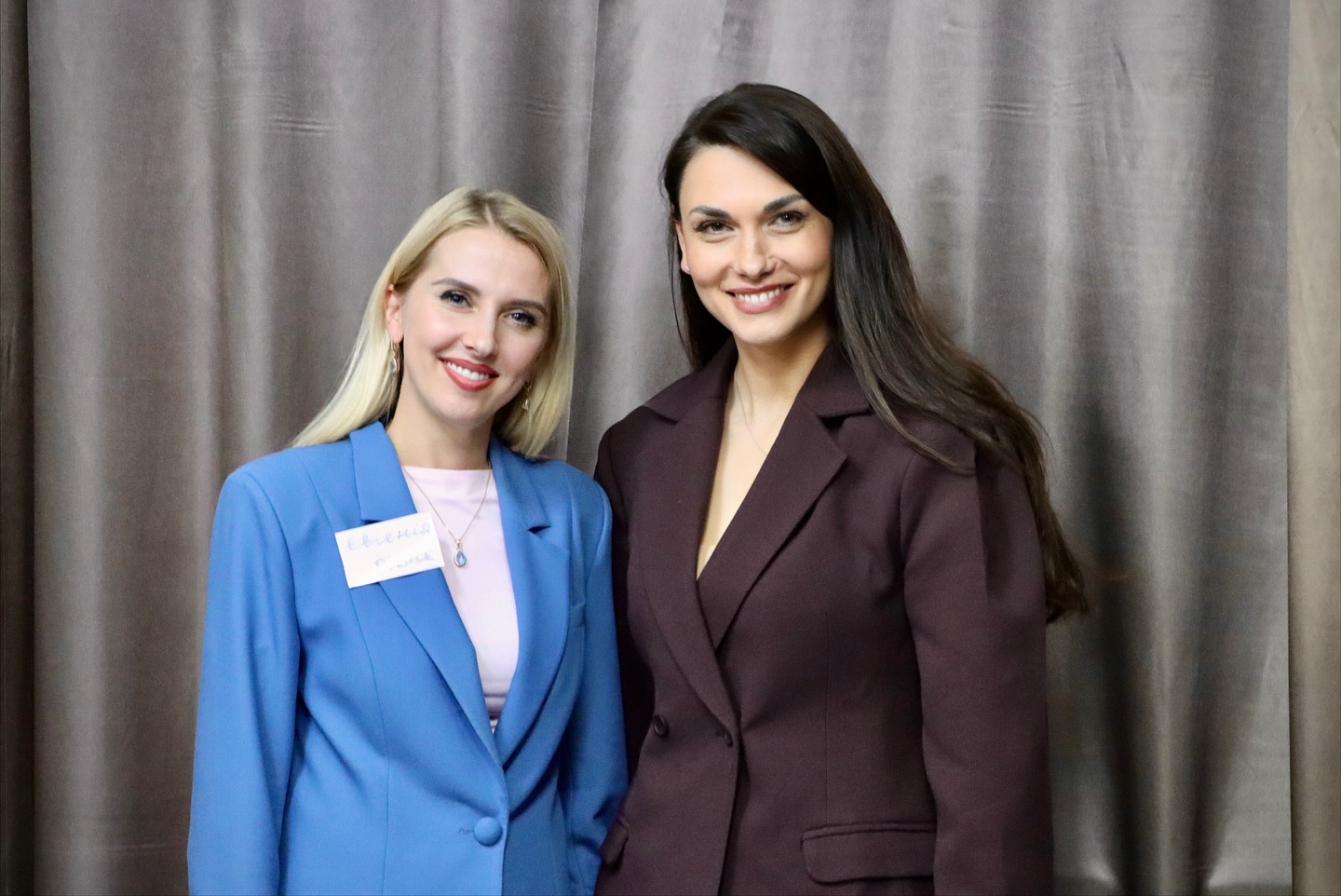 Дві жінки у ділових костюмах.