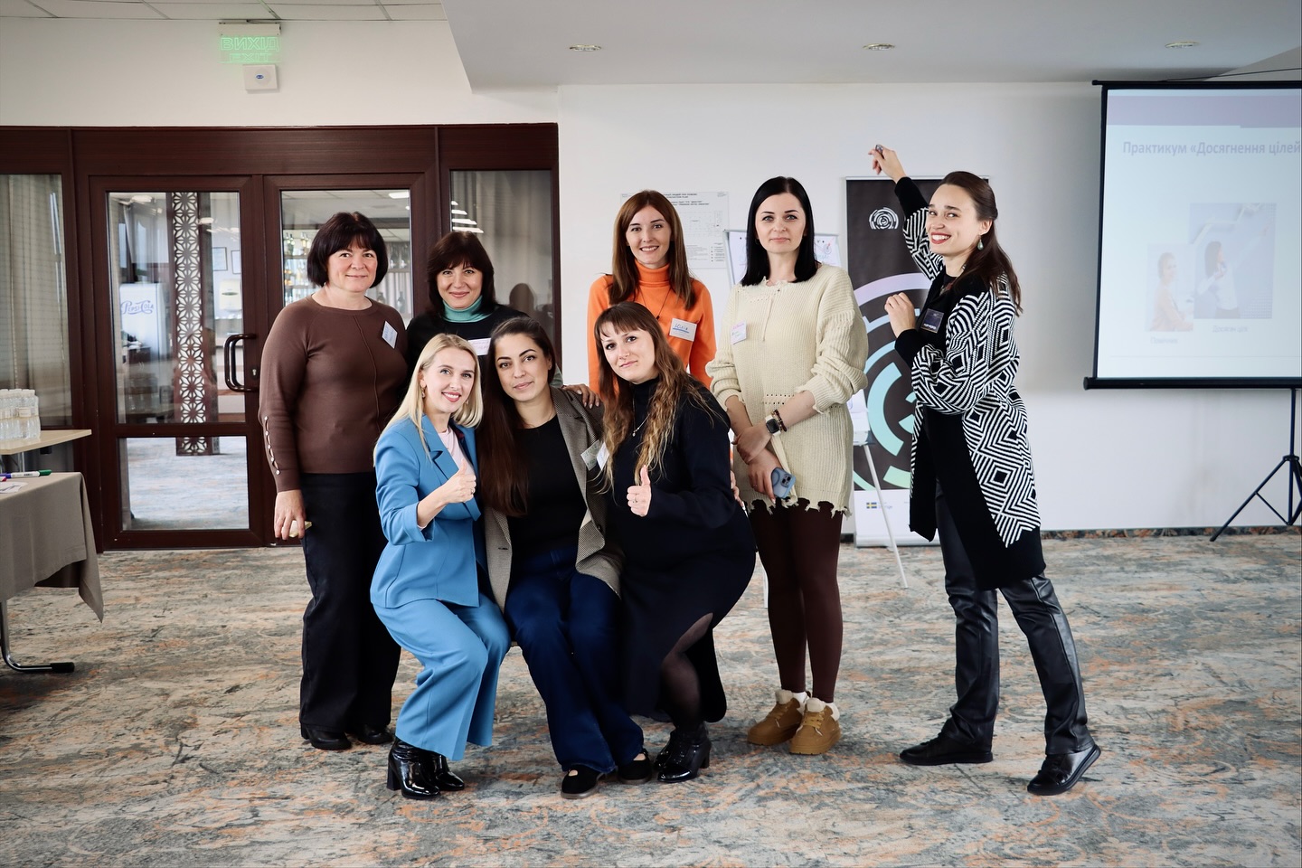 Вісім жінок позують для фото, у приміщенні.