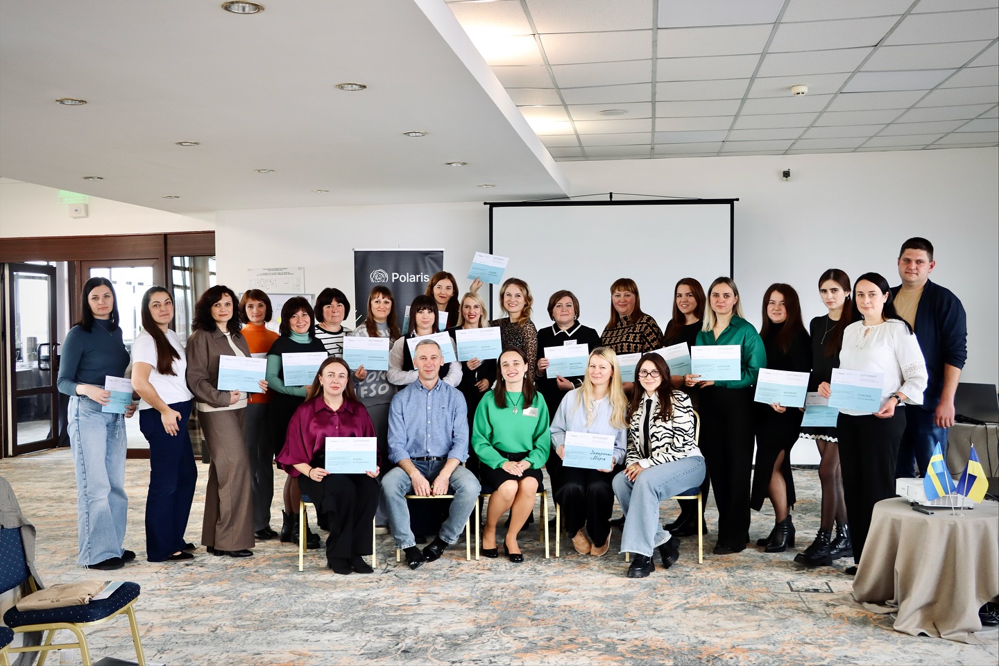 Група людей сидять у приміщенні та позують із сертифікатами.