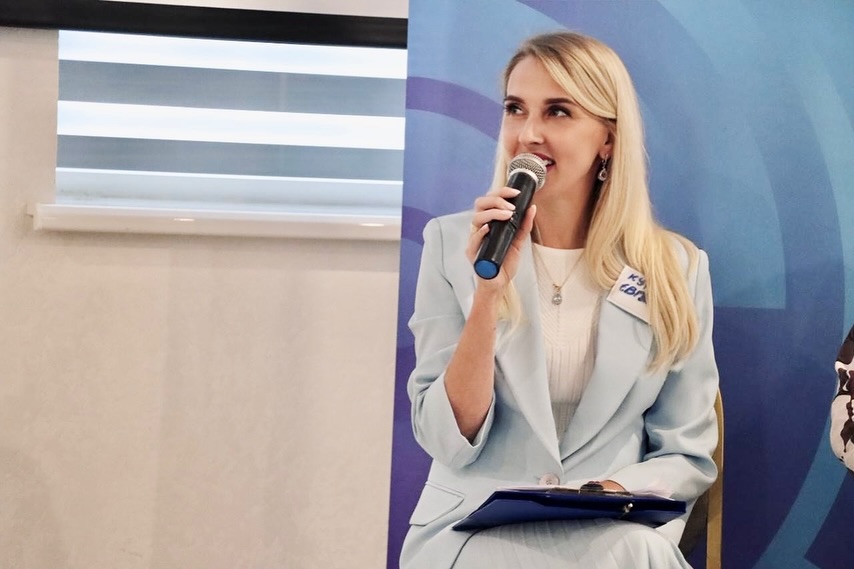Жінка із світлим волоссям розповідає щось в мікрофон.