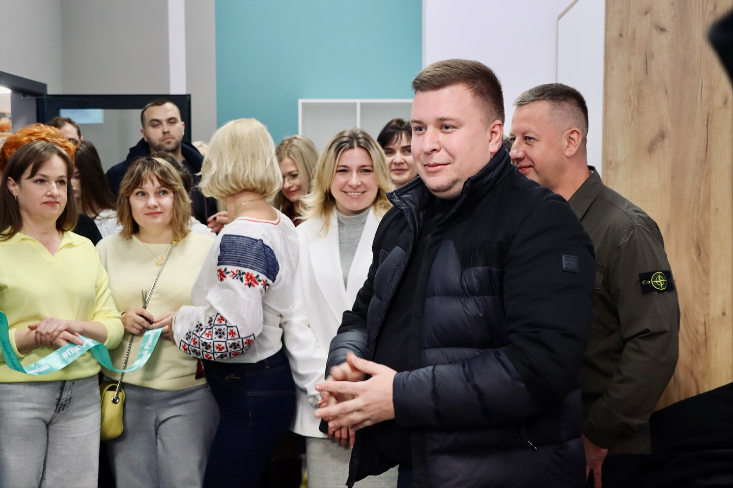 Чоловік перебуває у приміщенні, на задньому фоні - багато людей.