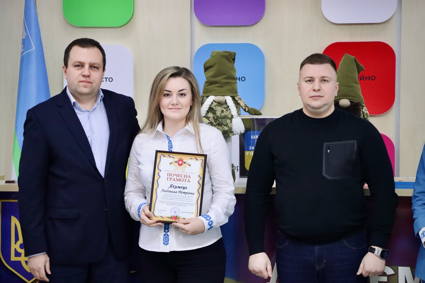 Двоє чоловіків та жінка позують для фото з грамотою.