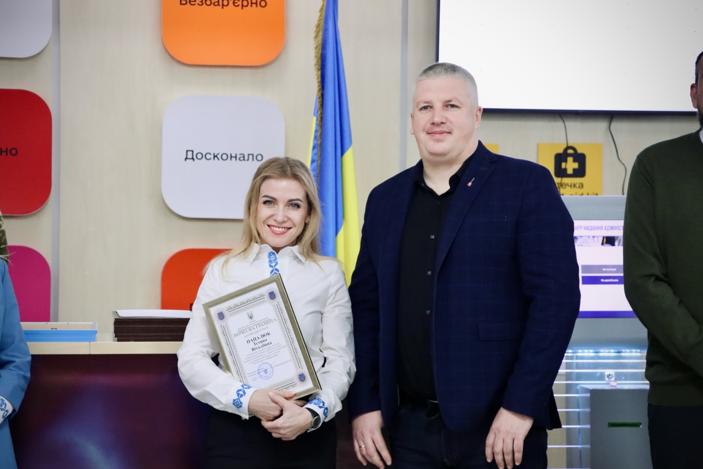 Жінка тримає подяку, біля неї стоїть чоловік