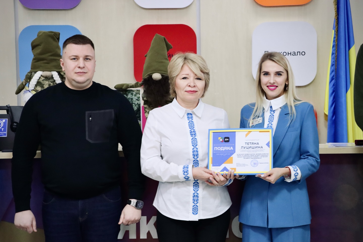 Дві жінки тримають подяку, біля них стоїть чоловік.