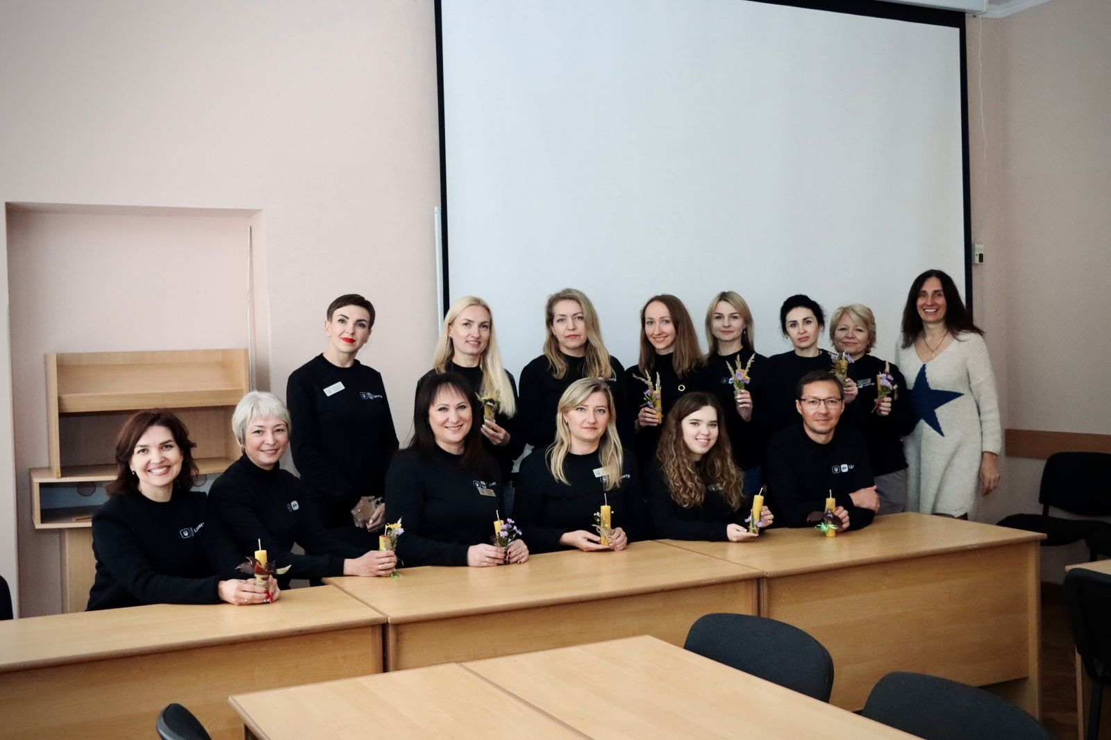 Групове фото у приміщенні, люди тримають у руках свічки та посміхаються.