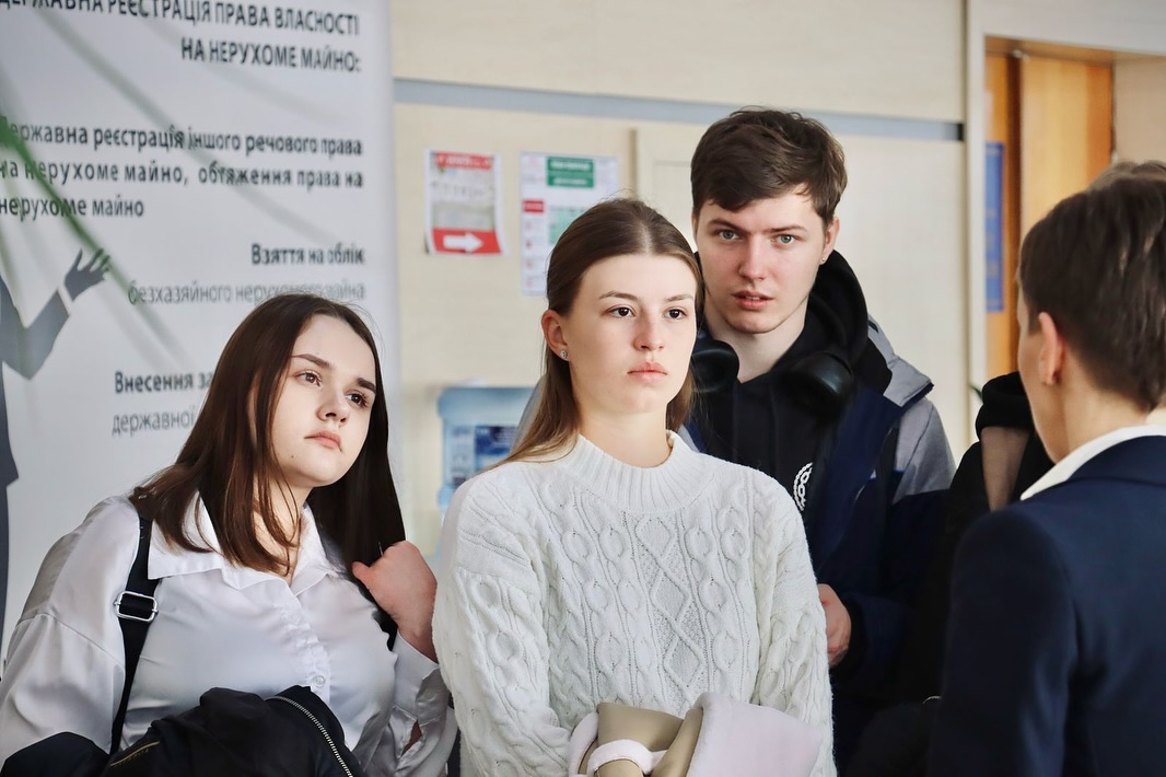 Двоє дівчат та хлопець перебувають у приміщенні.