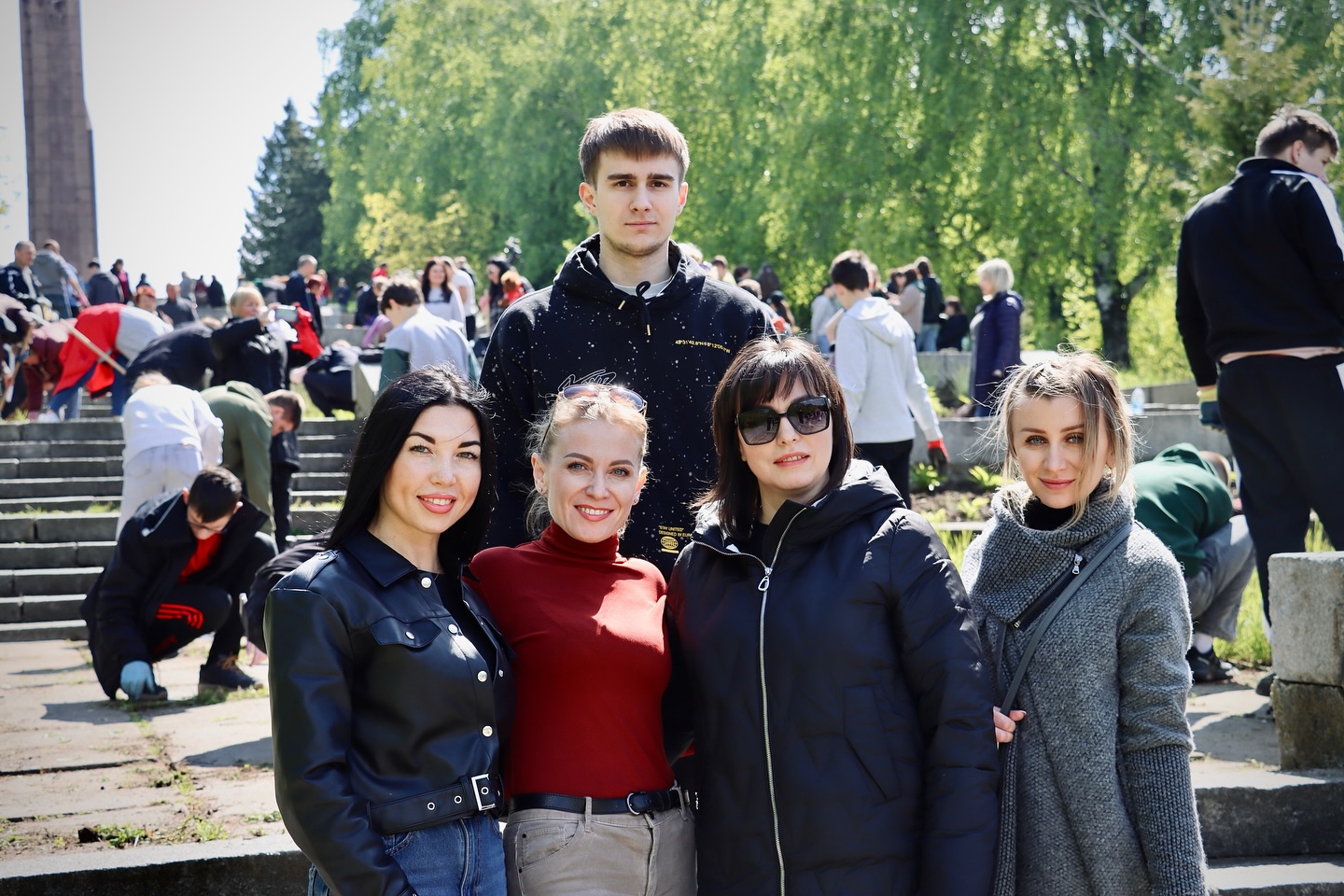 Чотири жінки та хлопець позують надворі.