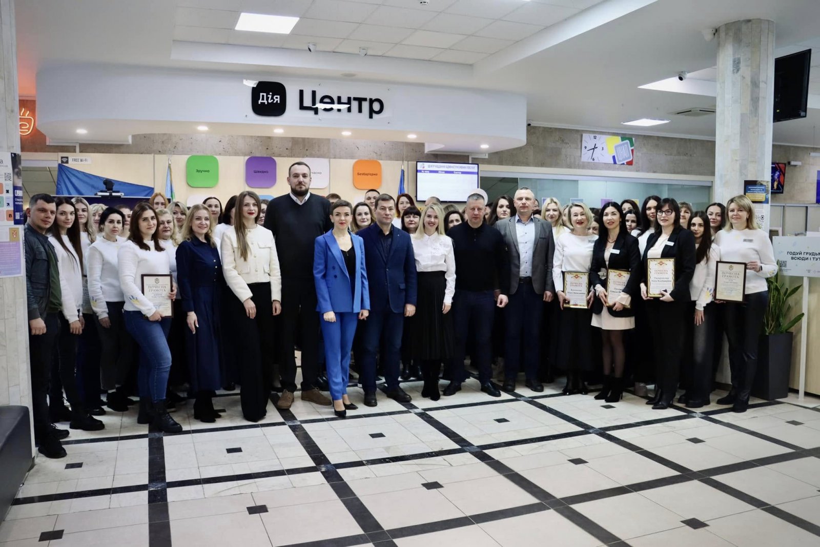 Чоловіки та жінки стоять у приміщені  ЦНАПу в місті Рівному.