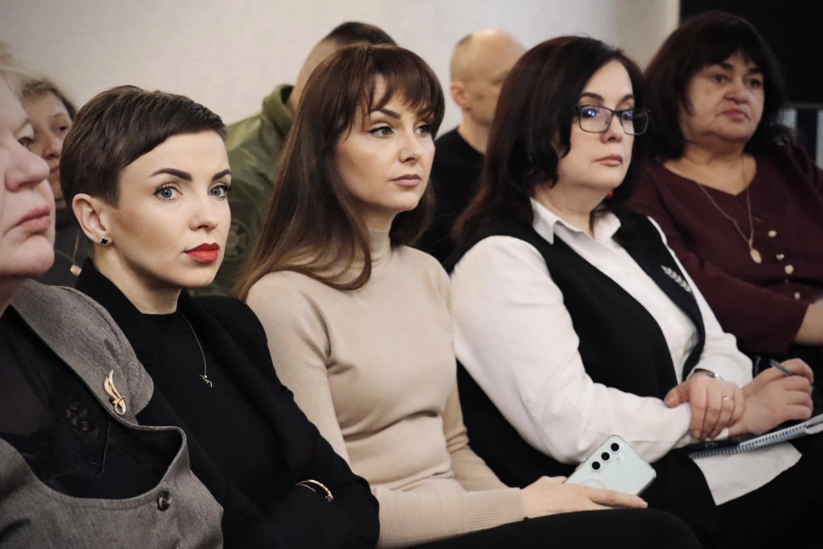 Жінки сидять у залі та беруть участи у діалоговій зустрічі 