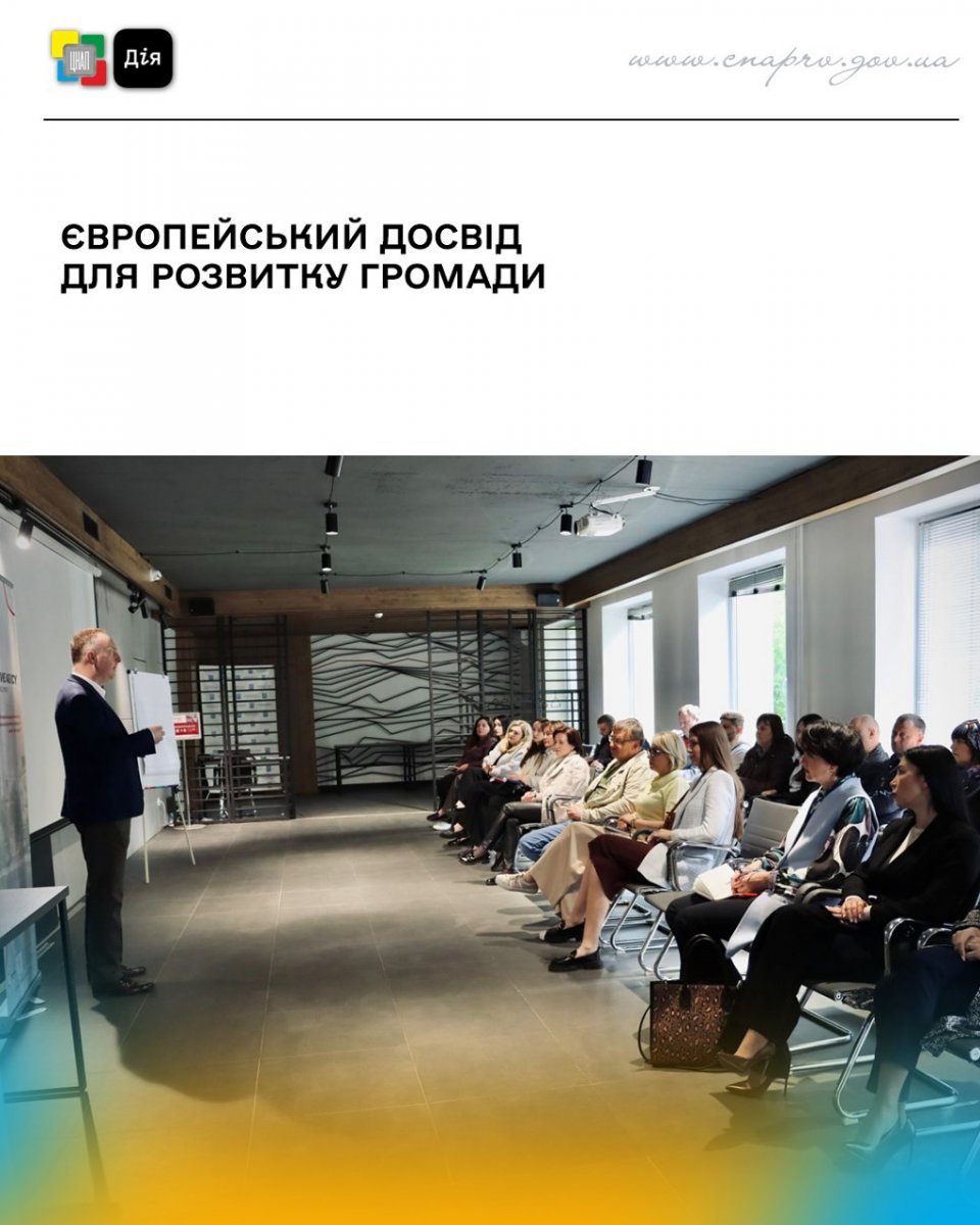 Багато людей сидять у приміщенні перед ними стоїть чоловік та щось розповідає.
