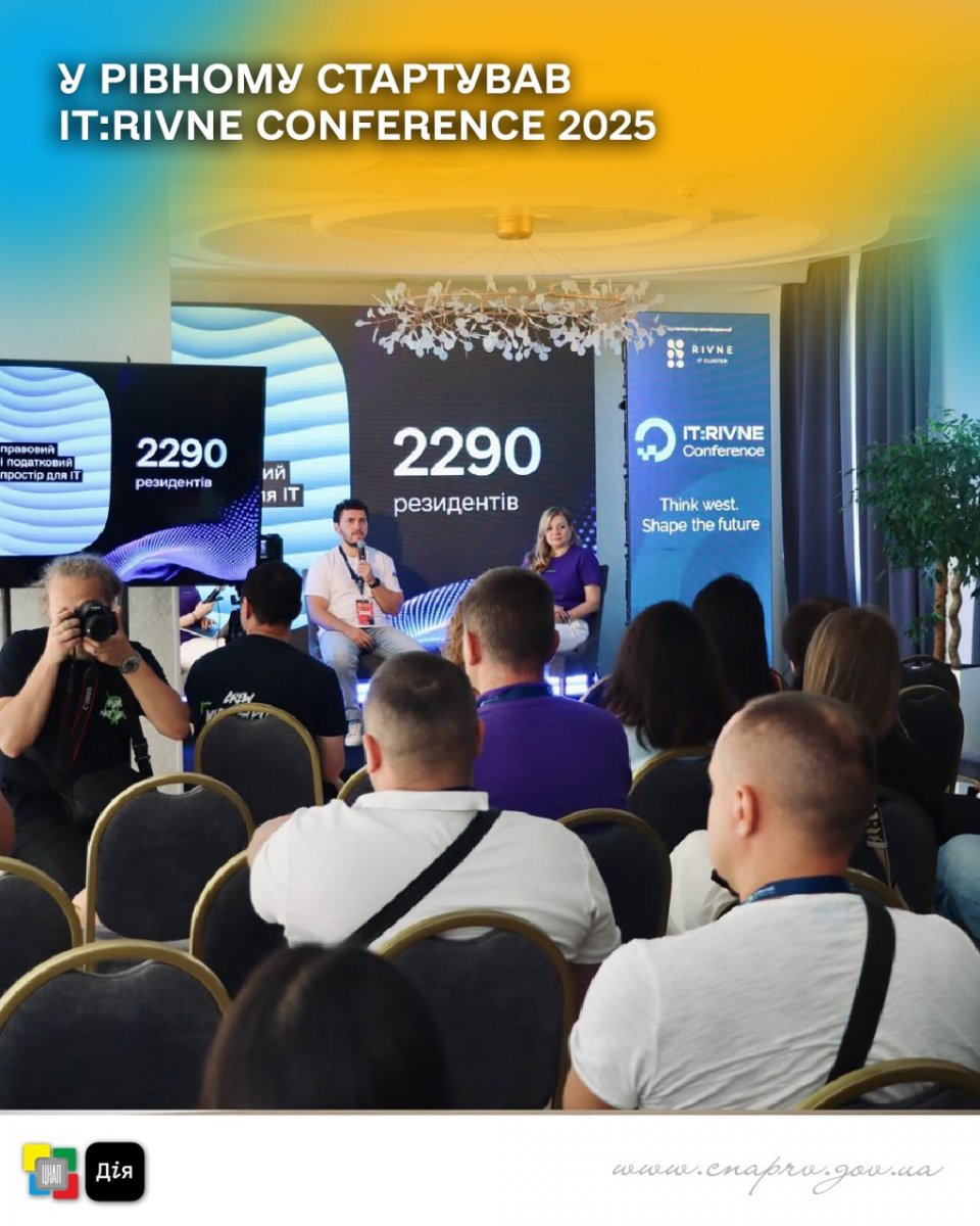 Чоловік з мікрофоном і жінка з планшетом на сцені, у залі сидять люди.