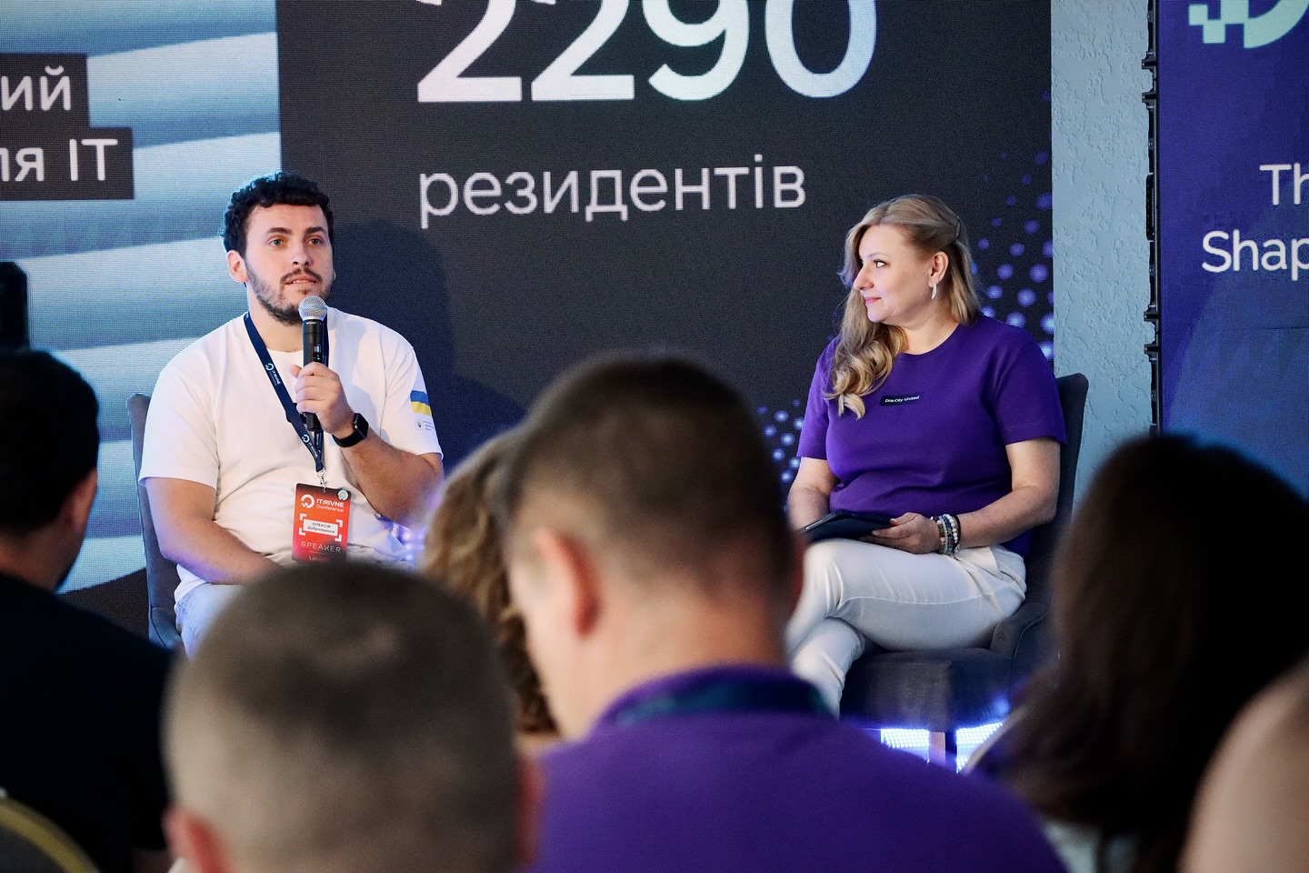 Чоловік з мікрофоном і жінка з планшетом на сцені.