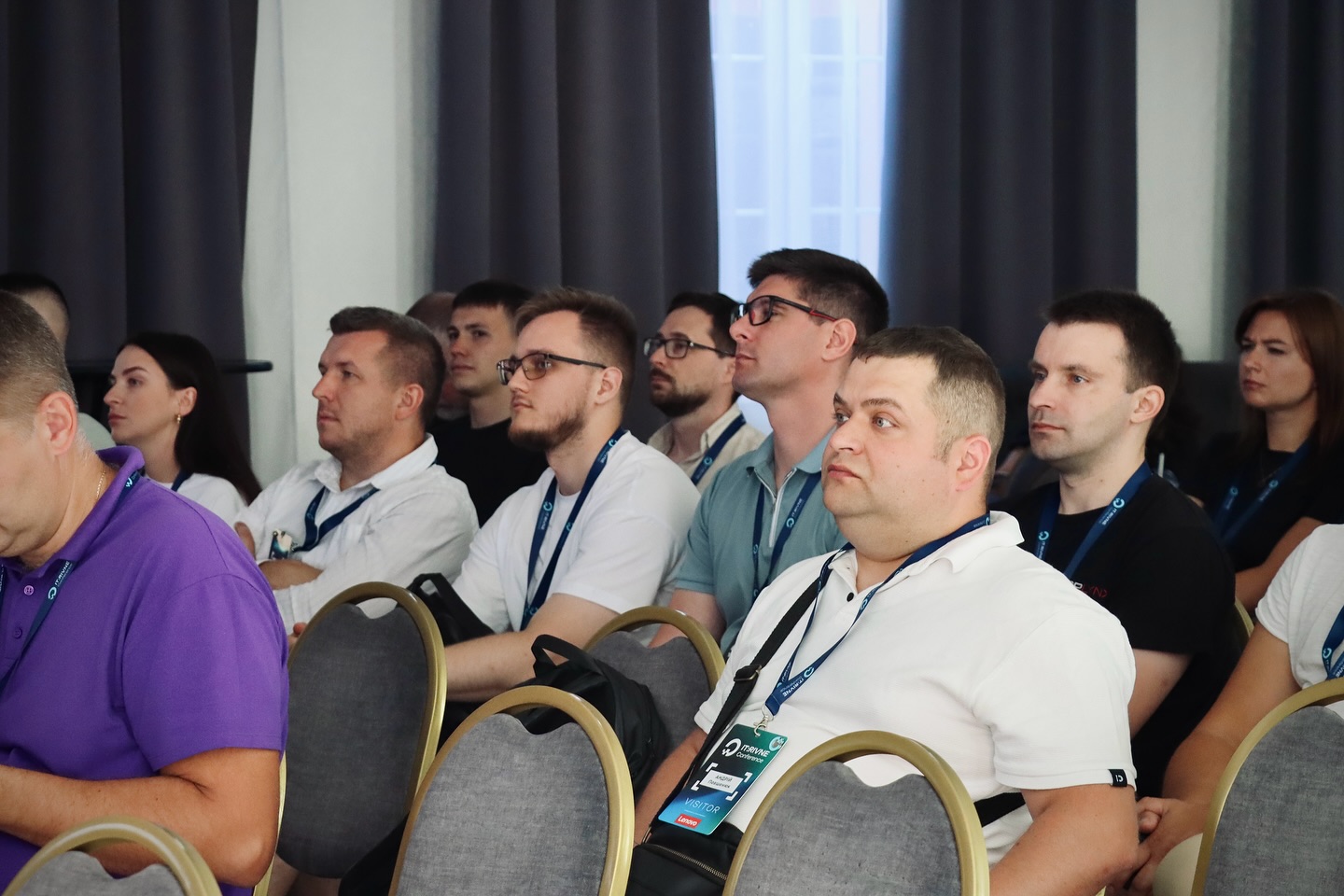 Учасники заходу сидять у залі.