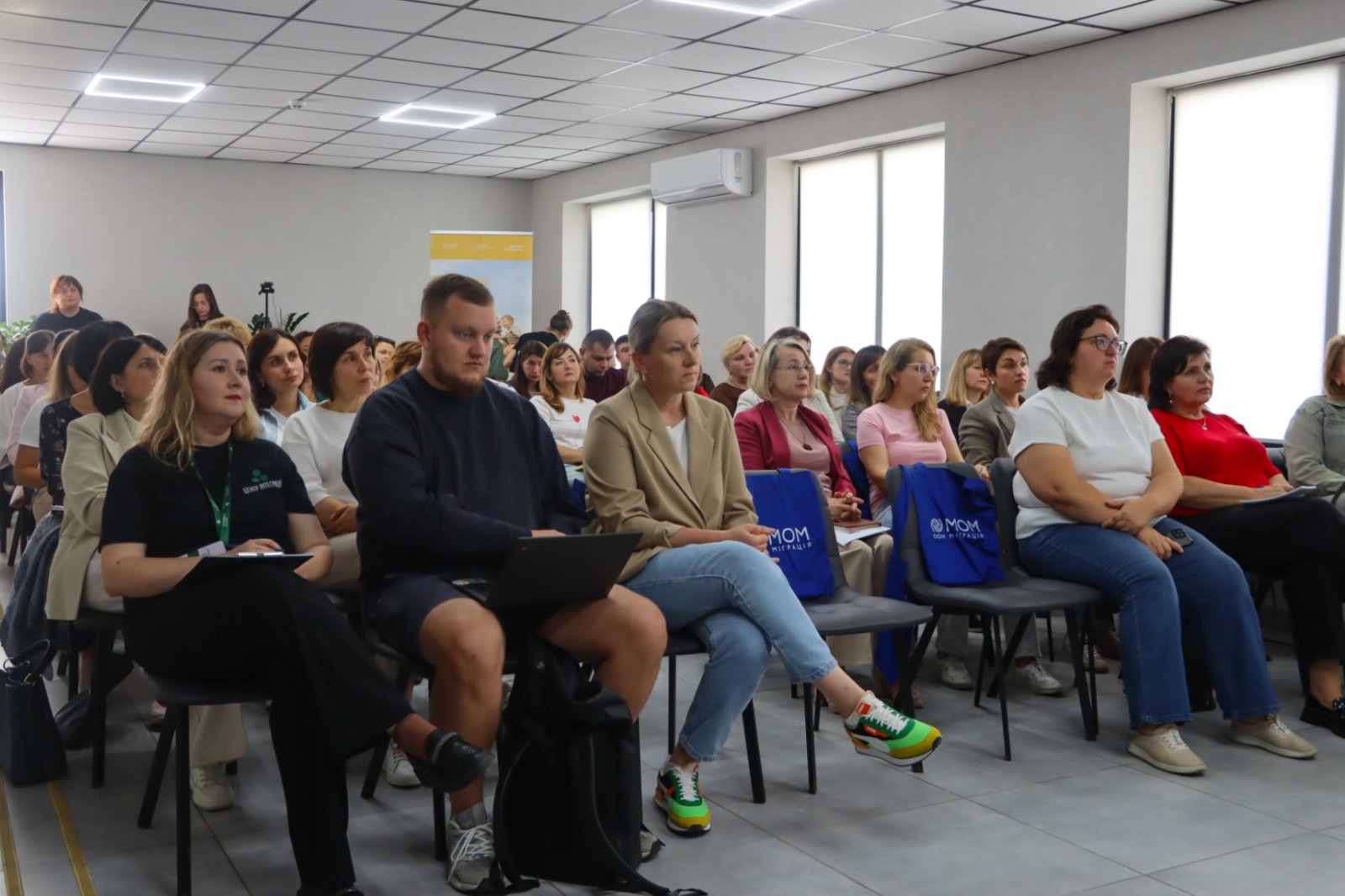 Багато людей сидять у приміщенні.