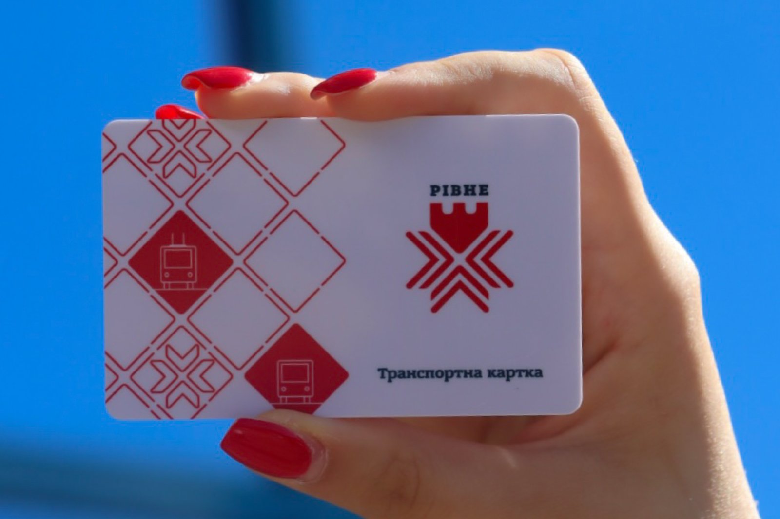 Транспортка картка у червоному і білому кольорах, у руці на синьому фоні.