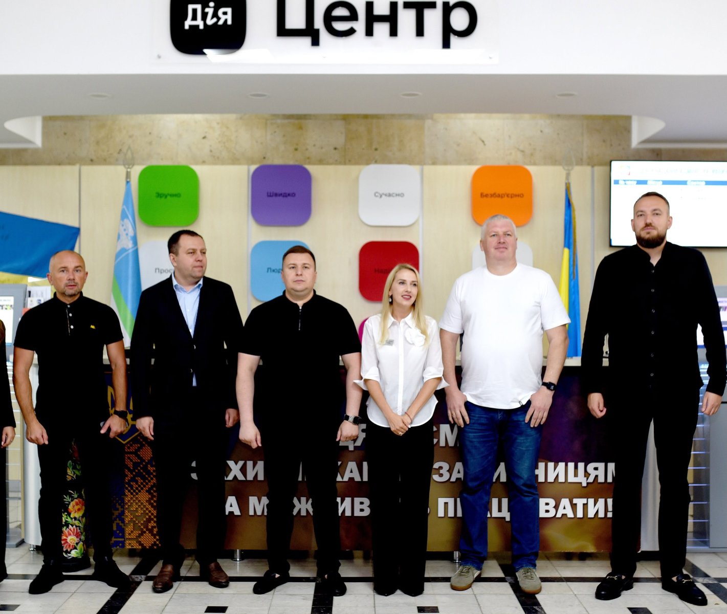 П'ять чоловіків та жінка стоять у приміщенні.