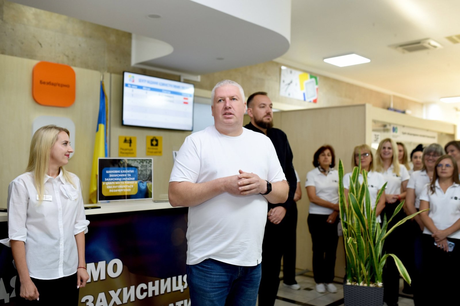 Чоловік у білій футболці, на задньому фоні - інші люди.