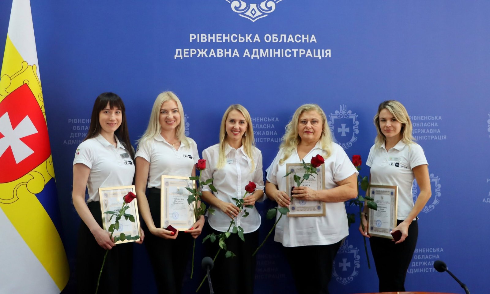 П'ять жінок у білому одязі з червоними трояндами у руках.