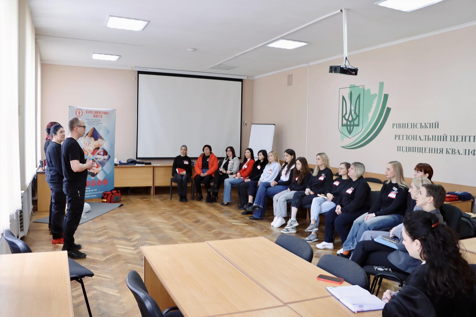 Чоловік в чорному одязі стоїть перед групою осіб