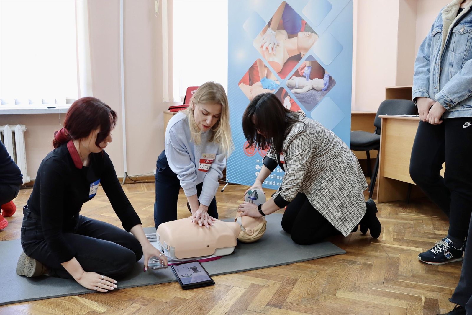 Дві жінки тренуються на манекені надавати першу домедичну допомогу