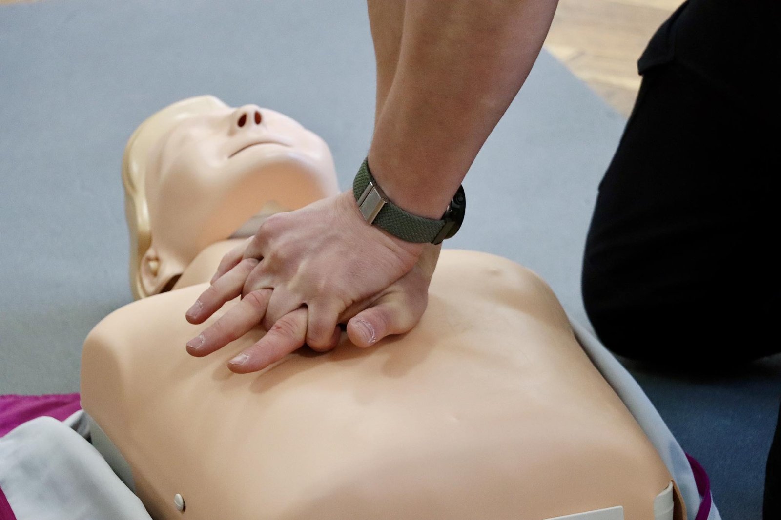 Руки виконують непрямий масаж серця на манекені.