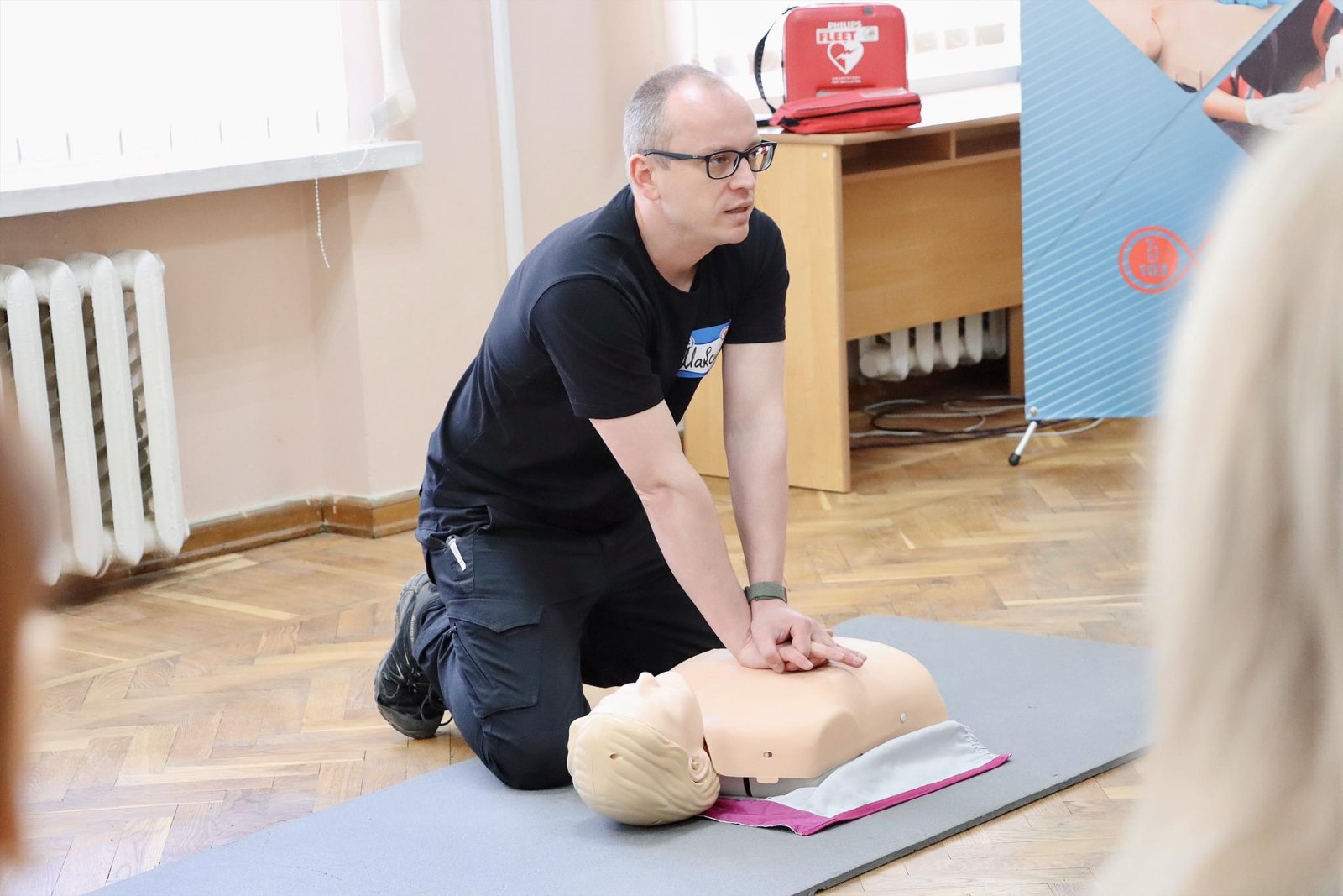 Чоловік демонструє на манекені непрямий масаж серця