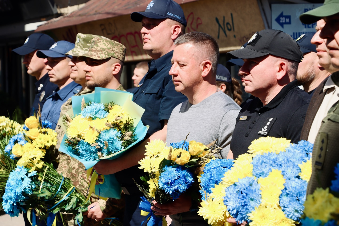Група чоловіків з букетами квітів.