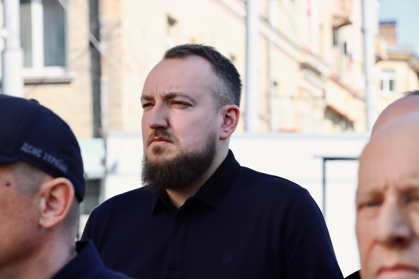 Чоловік з бородою у чорному одязі.