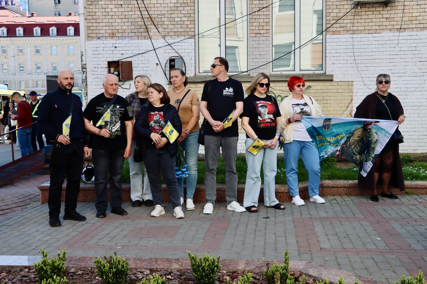 Група людей стоять з прапорами.