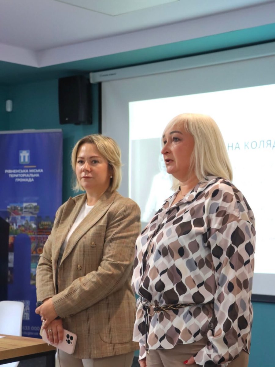 Дві жінки у діловому одязі перебувають у приміщенні.