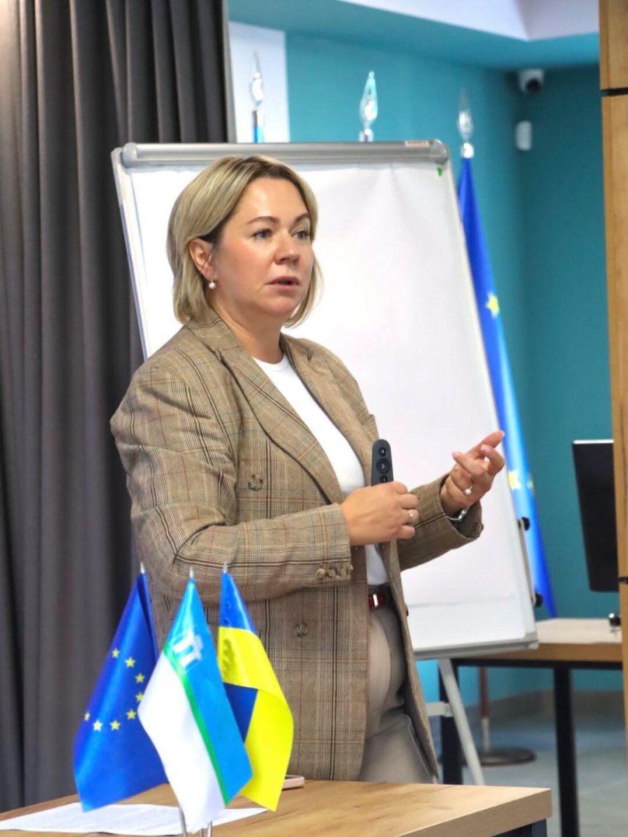 Жінка у діловому костюмі у приміщенні.