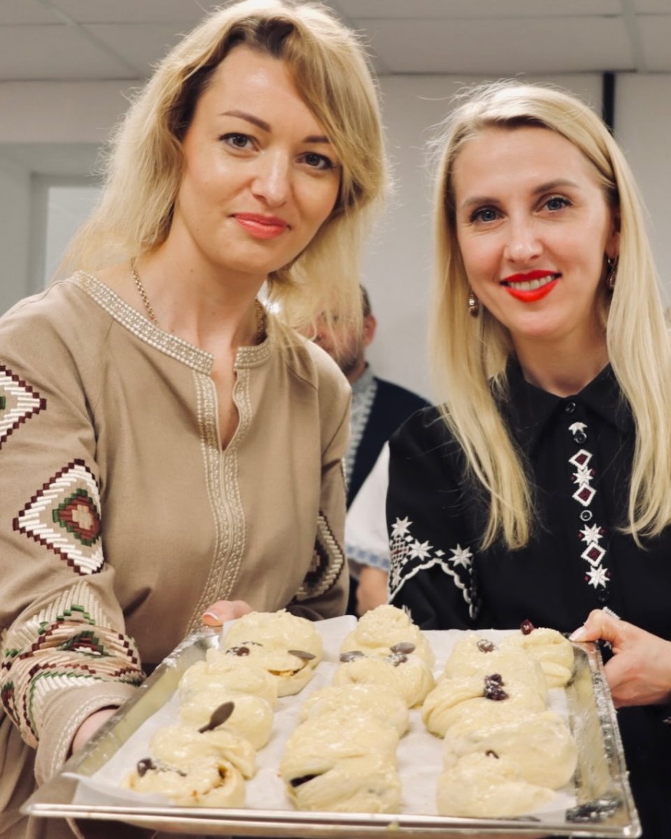 Дві жінки тримають деко з виробами з тіста.
