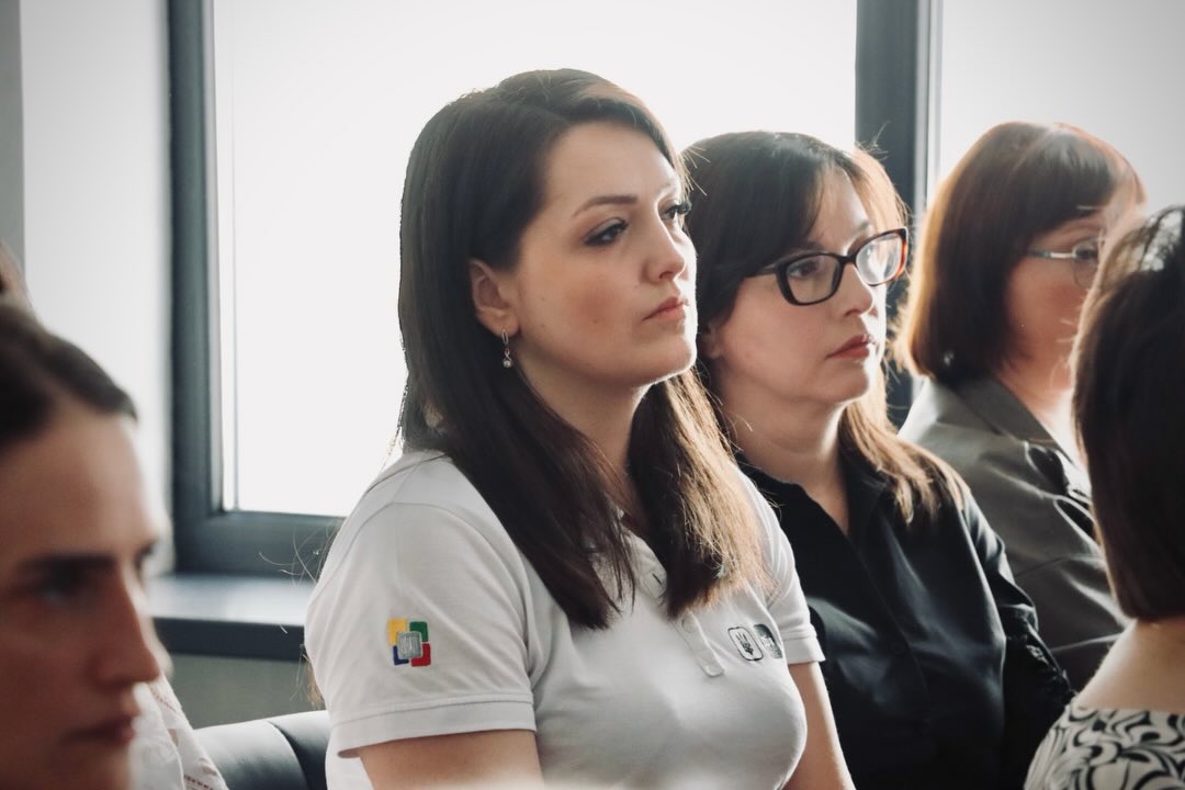 Декілька жінок сидять у приміщенні.