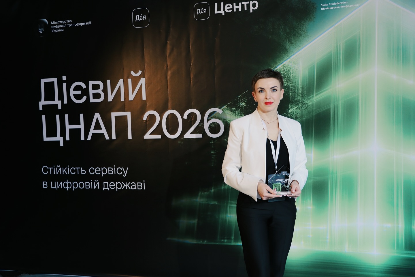 Жінка з короткою зачіскою позує з нагородою.