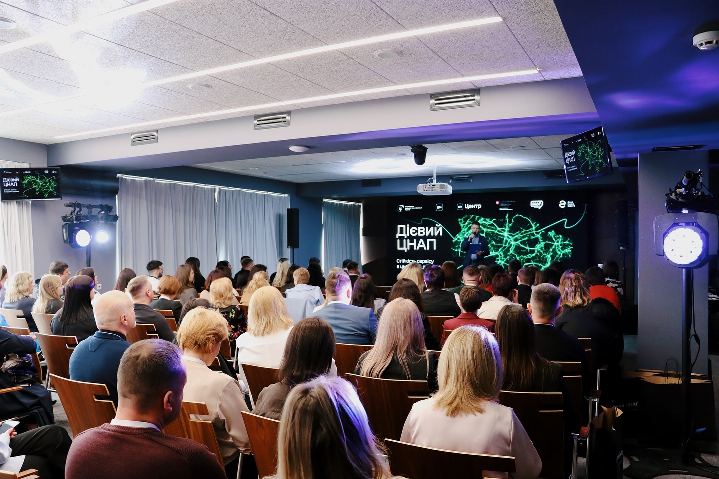 Багато людей сидить у приміщенні.